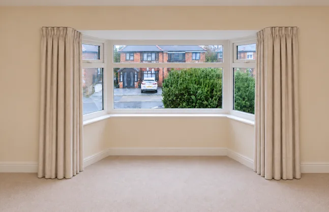 Curtains following an angled bay window and returning onto the room walls